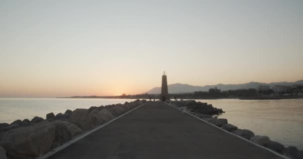 Woman In Sportswear Running Towards Lighthouse At Sunset — Video Stock