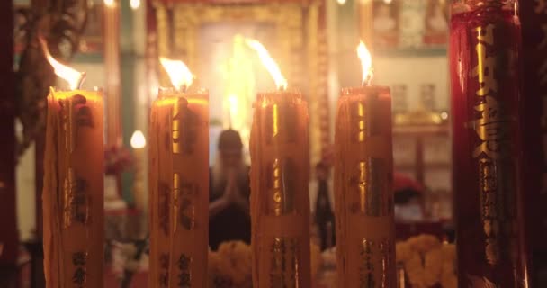 Close-up shot van brandende kaarsen als het aanbieden van binnen een boeddhistische kerk — Stockvideo