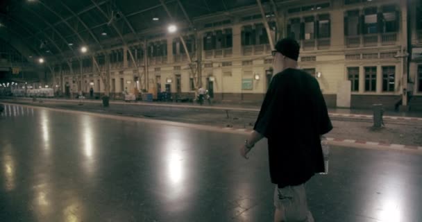 Panning Shot de um homem caminhando ao longo da plataforma em uma estação de trem — Vídeo de Stock