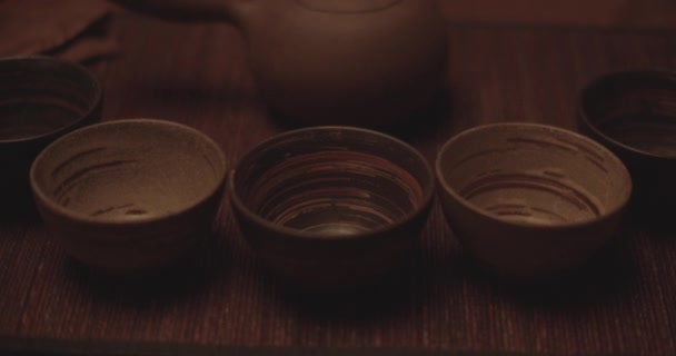 Tazas de té de cerámica alineadas en una mesa de madera — Vídeo de stock