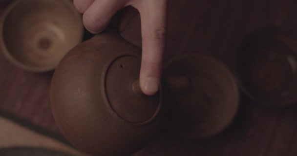 Focalizzata sulla visione sfocata delle mani dell'uomo versando acqua calda su tazze da tè in legno — Video Stock