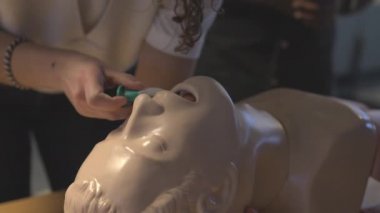 Bir kadının, bir mankenin ağzına sözlü hava yolu cihazı yerleştirirken yakın çekim.