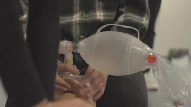 Person hält eine Taschenklappenmaske auf dem Mund eines Dummys, während ein anderer CPR macht — Stockvideo