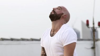 Adam boynunu geriye doğru uzatıyor ve sonra yan yana esnetiyor.