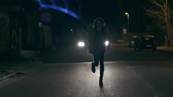 Young Man Running Away From A Lit Car On A Dark Street — Stock Video