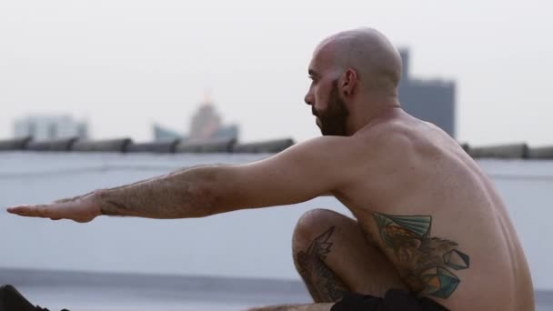 Татуированный парень балансирует на одной ноге, в то время как его руки вытянуты вперед — стоковое видео