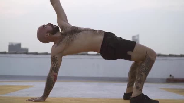 Homme effectue un exercice de yoga de flexion du dos avec les deux pieds et une main sur le sol — Video