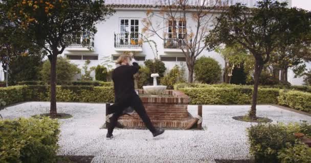 Людина виконує бойові мистецтва в офіційному саду — стокове відео