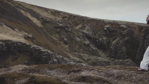 Uomo capelli ricci a piedi verso la montagna trascina un pezzo di tessuto sottile — Video Stock