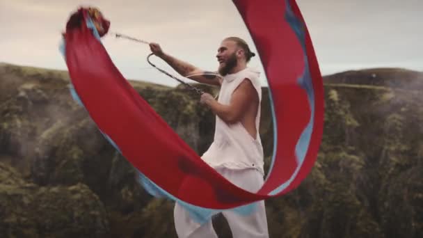Lykkelig fyr som svinger over et rødt Chiffon-stoff med blått Hem mot luften – stockvideo