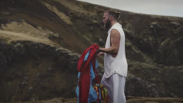 Man Walking Towards A Mossy Mountain Launching A Sheer Fabric In The Air — Stock Video