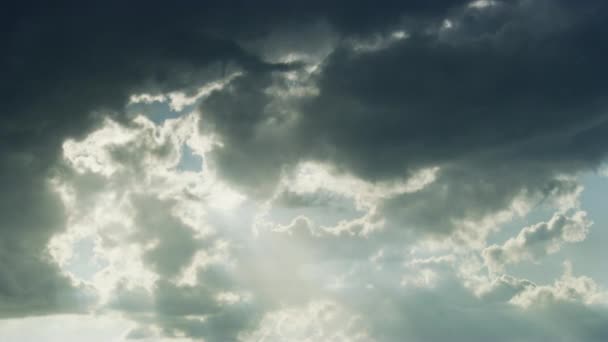 Sötét szürke felhők hágnak át, hogy utat engedjenek a dicsőséges napsütésnek. — Stock videók