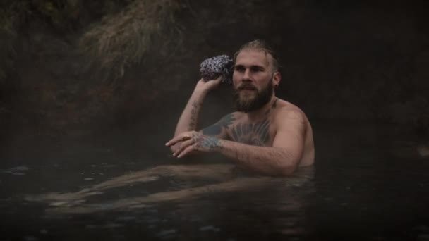 L'homme jette un tissu comme il se détend sur un ruisseau — Video