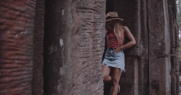 Blond kvinne som lener seg mot en struktur mens hun posisjonerer seg for kamera – stockvideo