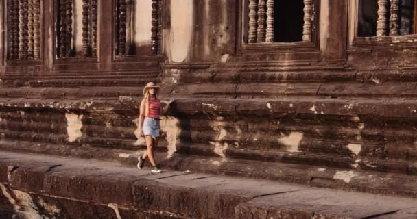 Um modelo feminino jovem que caminha para a câmera usando um chapéu de palha marrom — Vídeo de Stock