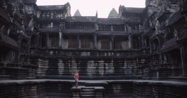 Una joven turista posando fuera de las paredes de un antiguo templo permanece — Vídeos de Stock