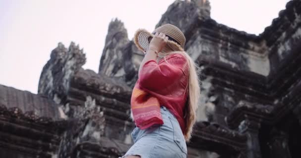 Câmera colocada em um ângulo baixo enquanto uma modelo feminina posa fora de uma ruínas do templo — Vídeo de Stock