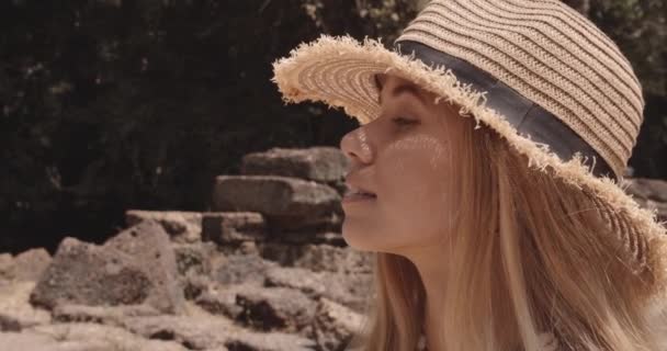 En attraktiv blond ung kvinna som tittar på strukturerna medan solen — Stockvideo