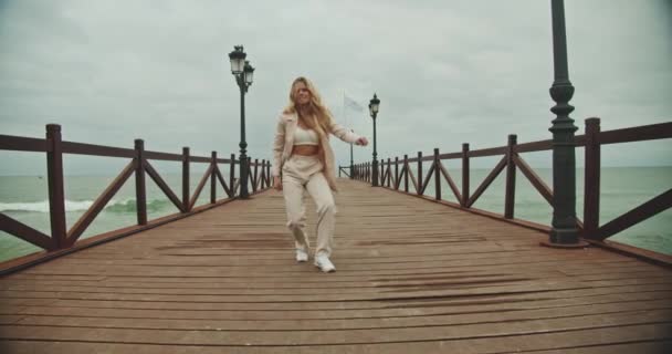 Vrouw dansend in pak op houten pier — Stockvideo