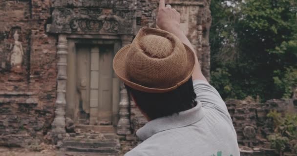 Το άτομο δείχνει με το δάχτυλό του απομεινάρια μιας παλιάς δομής στην Καμπότζη — Αρχείο Βίντεο