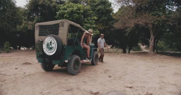 Um homem de cabelos pretos e loira modelo feminino vai para baixo em um jipe verde — Vídeo de Stock