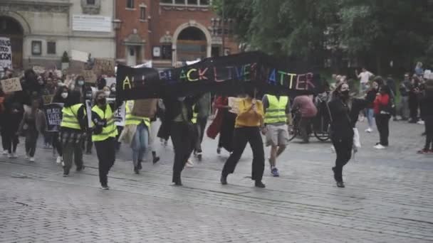 Διαδηλωτές κρατώντας ένα μαύρο αφίσα ράλι με γράμματα γραμμένο σε αποχρώσεις του ουράνιου τόξου — Αρχείο Βίντεο