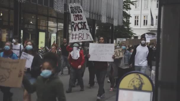 Un disparo constante de manifestantes marchando con sus afiches de manifestación en una pequeña carretera — Vídeos de Stock