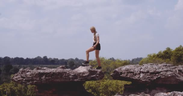 Blondynka podróżniczka skacze z jednej skały do drugiej — Wideo stockowe