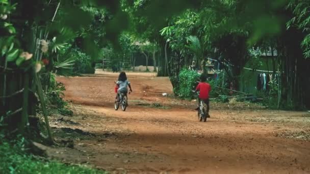 Bambini in bicicletta Circondato da alberi verdi lussureggianti — Video Stock