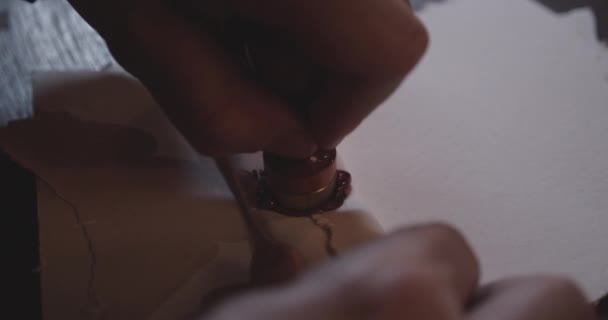 Hände, die Druck auf eine Briefmarke ausüben, während sie ein Papier mit rotem Wachs versiegelt — Stockvideo
