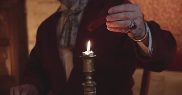 Eine Person schmilzt rotes Wachs über einer Kerzenflamme — Stockvideo