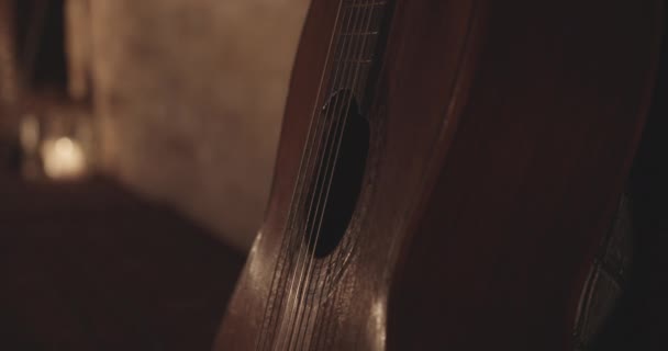 Тело деревянной акустической гитары опирается на бетонную стену — стоковое видео