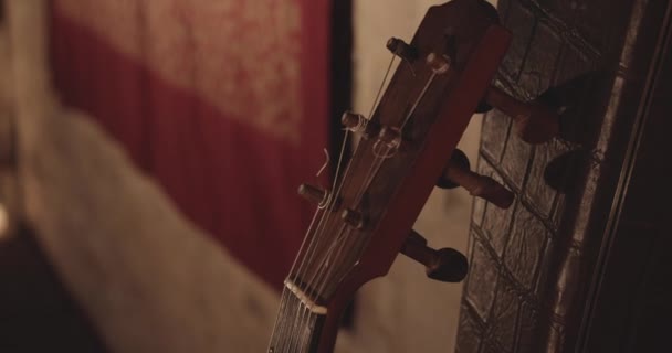 Houten akoestische gitaar headstock leunt op een bruin leer oppervlak — Stockvideo