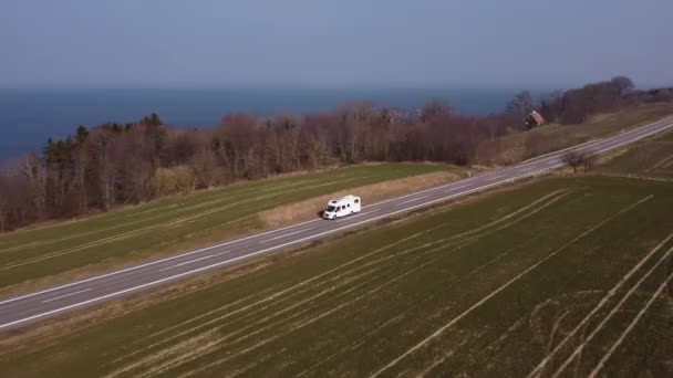 Camper bianco che si muove verso un sentiero asfaltato circondato da ampie terre — Video Stock