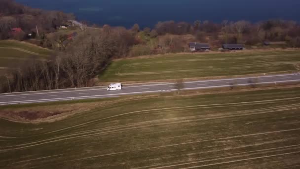 Drohnenschuss eines reisenden weißen Kastenwagens inmitten von Feldern — Stockvideo
