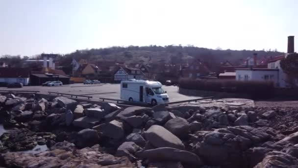 Drohne umkreist einen weißen Kastenwagen, der mit großen Steinen am Ufer geparkt ist — Stockvideo