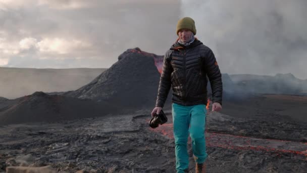 Fotógrafo caminando frente al flujo de lava desde el eruptivo volcán Fagradalsfjall — Vídeo de stock
