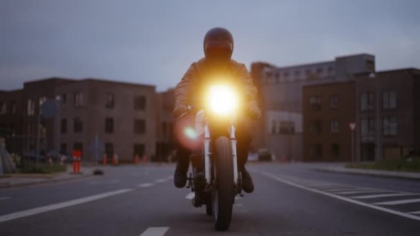 Un tir de pistage d'une personne conduisant une moto sur une rue inactive un crépuscule — Video