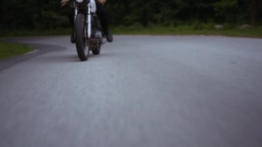 Dar bir yolda, yemyeşil ormanın arka planında motosiklet gezisi.