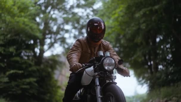 Persoon die een motorfiets rijdt op een weg langs de weelderige groene bomen op Clear Skies — Stockvideo