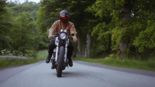 Tracking Shot of a Motorcycle on a Narrow Road Rodeado de frondosos árboles forestales — Vídeos de Stock