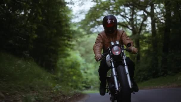 Человек за рулем мотоцикла по узкой дороге в лесу — стоковое видео