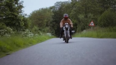 Dar bir yolda pürüzsüz sürülen motorsiklet Etrafı yemyeşil ağaçlarla çevrili