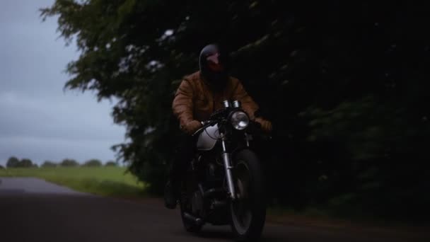 Motorfiets met de achtergrond van een weelderig groen veld onder de grijze kies — Stockvideo