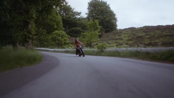 Мотоцикл на бетонной дороге на фоне пышного леса — стоковое видео