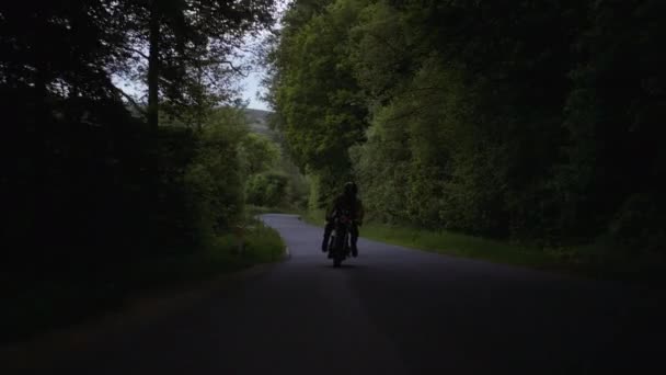 Roue de moto voyageant sur le sol en béton gris et vue sur la forêt luxuriante — Video