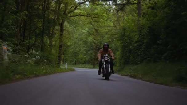 Motociclo guidato su una strada di cemento con lo sfondo di una ricca foresta — Video Stock
