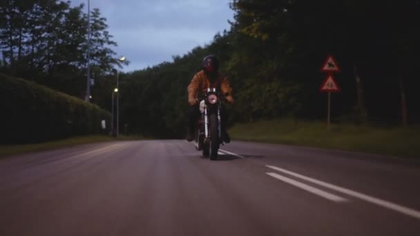 Motociclo guidato su una strada di cemento con lo sfondo di lampioni — Video Stock