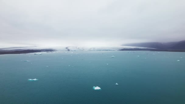 Icebergs éparpillés dans l'océan avec vue sur les montagnes sur ciel clair — Video