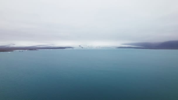 Océan bleu avec vue sur les montagnes enneigées sous le ciel clair — Video